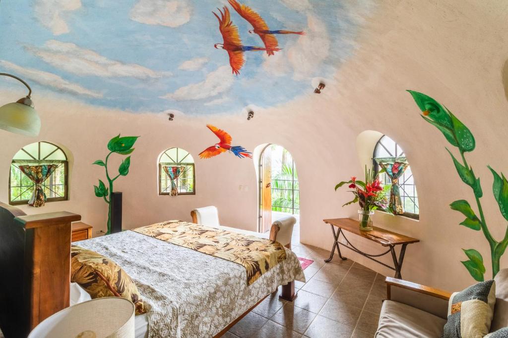 a bedroom with a bed and birds on the wall at Boutique Hotel Las Cascadas in Manuel Antonio