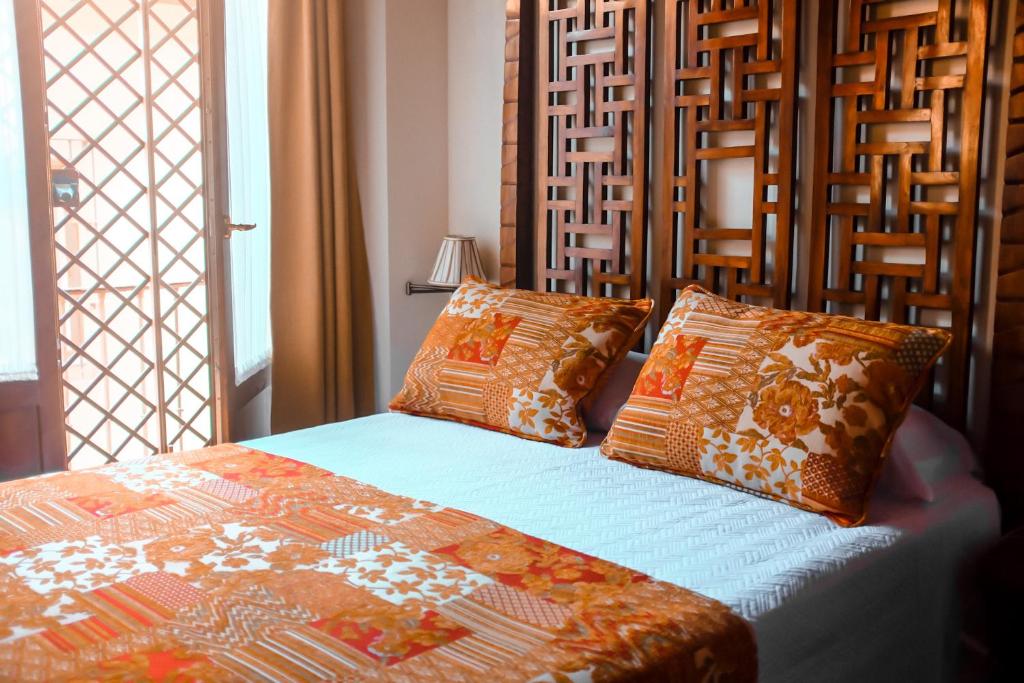 - une chambre avec un lit doté d'oreillers orange et blancs dans l'établissement Apartamentos en pleno centro, Aljibe Rodrigo del Campo 1B, à Grenade