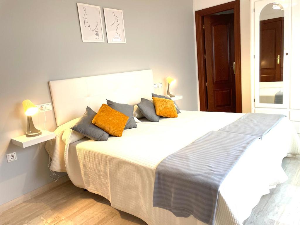 a bedroom with a large bed with orange and blue pillows at Apartamento San Francisco in Lucena