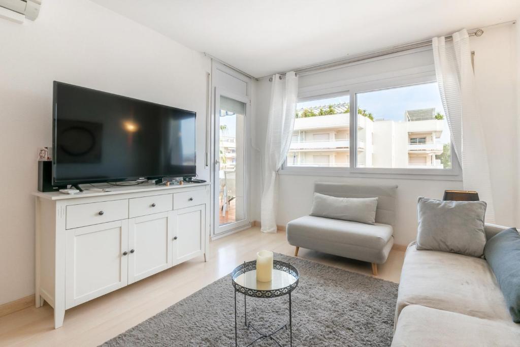sala de estar con sofá y TV de pantalla plana en Apartamento con vista piscina en Rosas