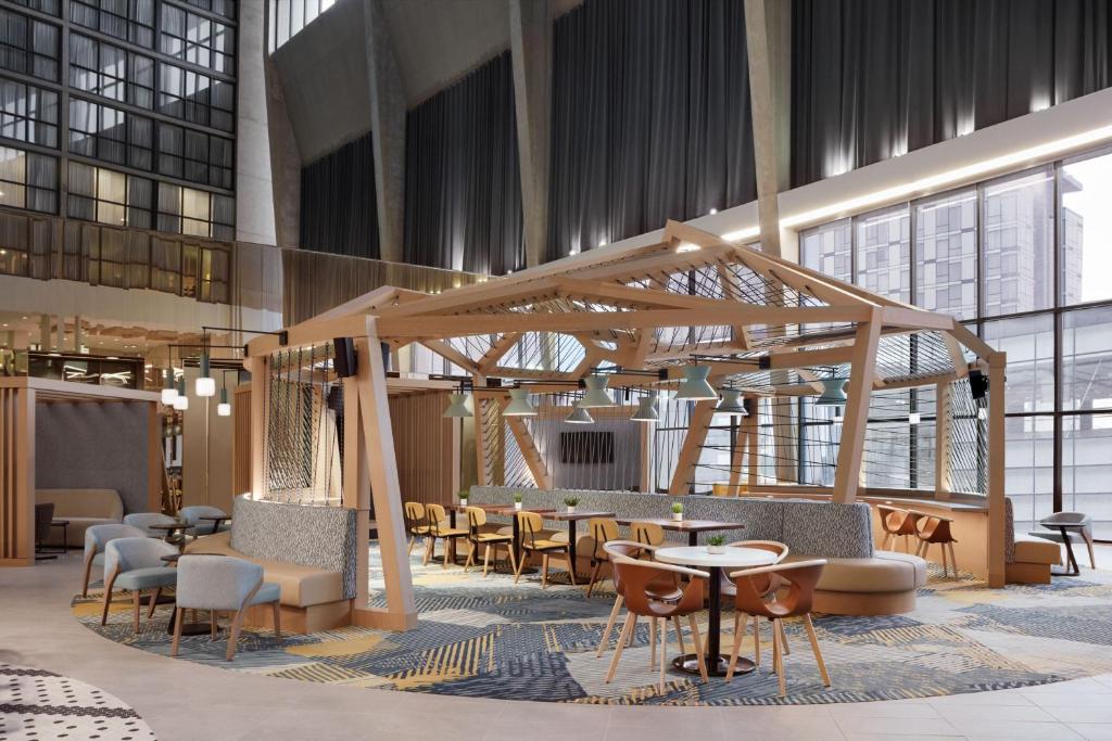カルガリーにあるDelta Hotels Calgary Airport In-Terminalの建物内のテーブルと椅子のあるロビー