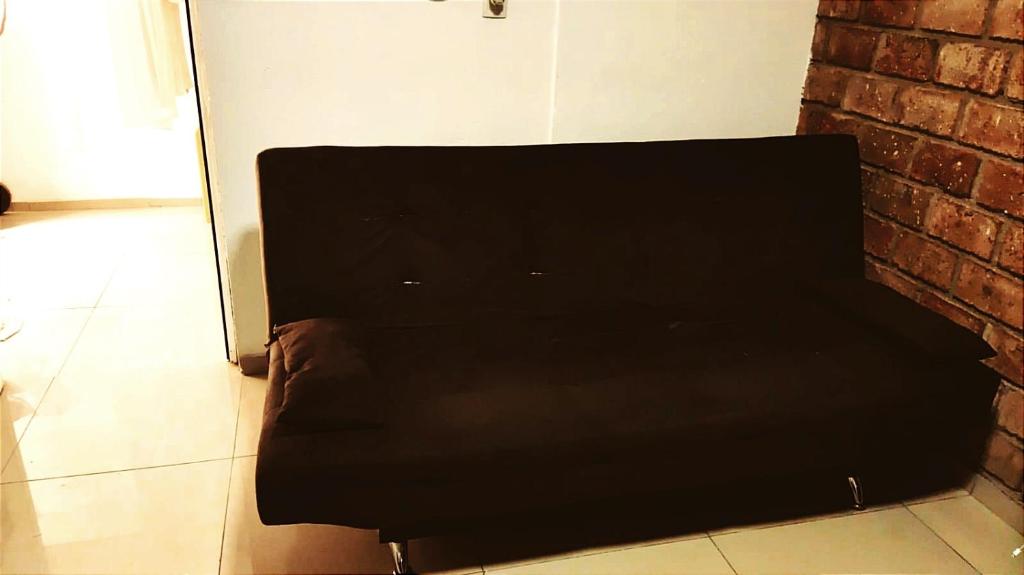 un sofá negro sentado junto a una pared de ladrillo en Sombra, en Ciudad de la Costa
