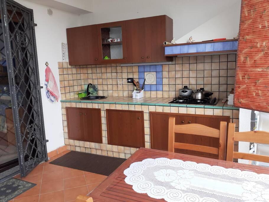 una cocina con armarios marrones y una mesa en una habitación en Da Maria casa con vista mare e monti, en Maierà