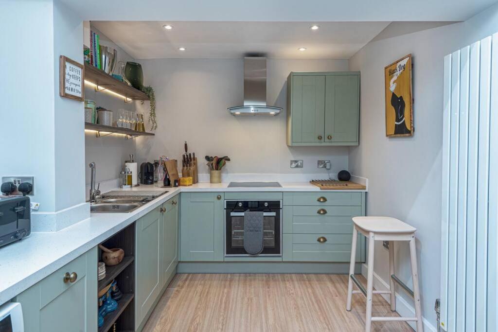 a kitchen with green cabinets and a counter top at Glanrhyd Townhouse in Central Dolgellau with Parking and Bike Storage in Dolgellau