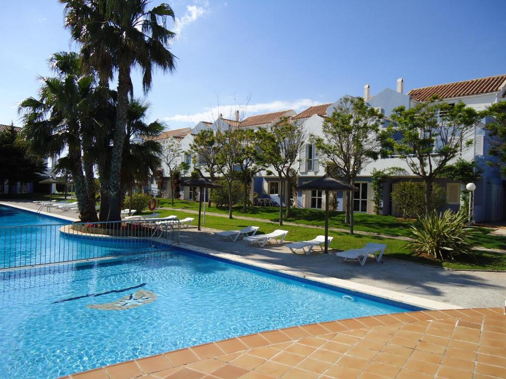 una grande piscina con sedie, alberi ed edifici di Club Ciudadela a Son Xoriguer