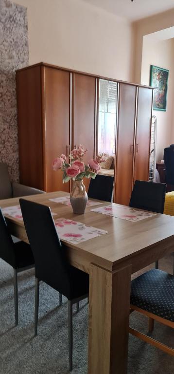 a wooden table with a vase of flowers on it at Oroszlán Apartman in Szeged