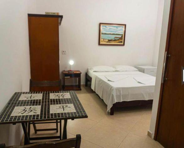 um quarto de hotel com duas camas e uma mesa em Pousada do Itaguá em Ubatuba