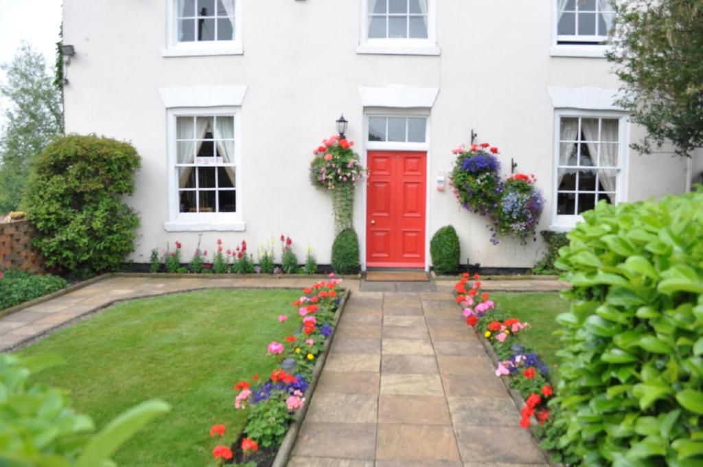 una casa blanca con una puerta roja y flores en Holden House, en Shardlow