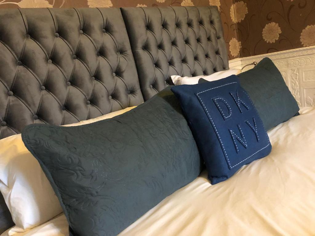 a bed with a black headboard with a blue pillow at Ashfield Hotel in Huddersfield