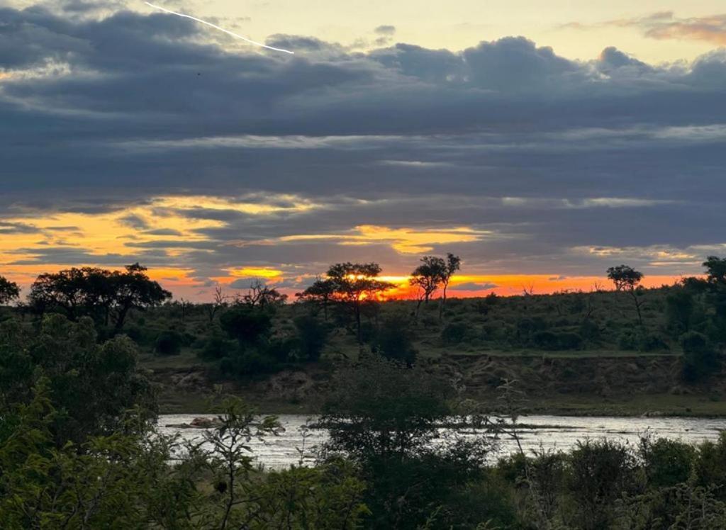a sunset over a river in a field at Croc's Nest in Marloth Park