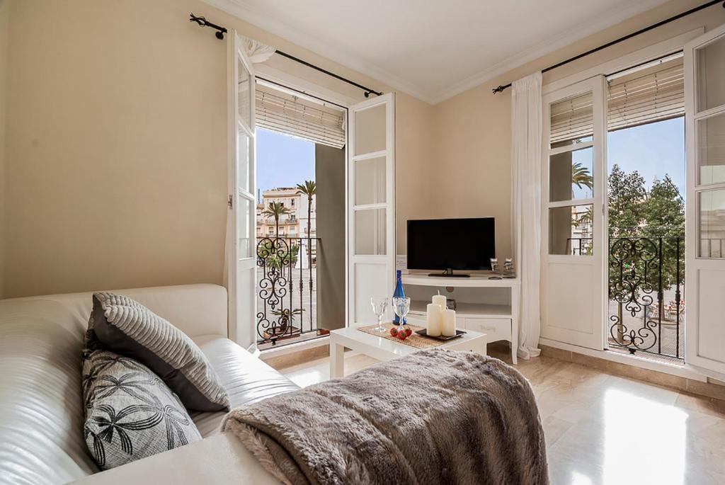 a living room with a couch and a tv at Little Sopranis Little Apartments in Cádiz