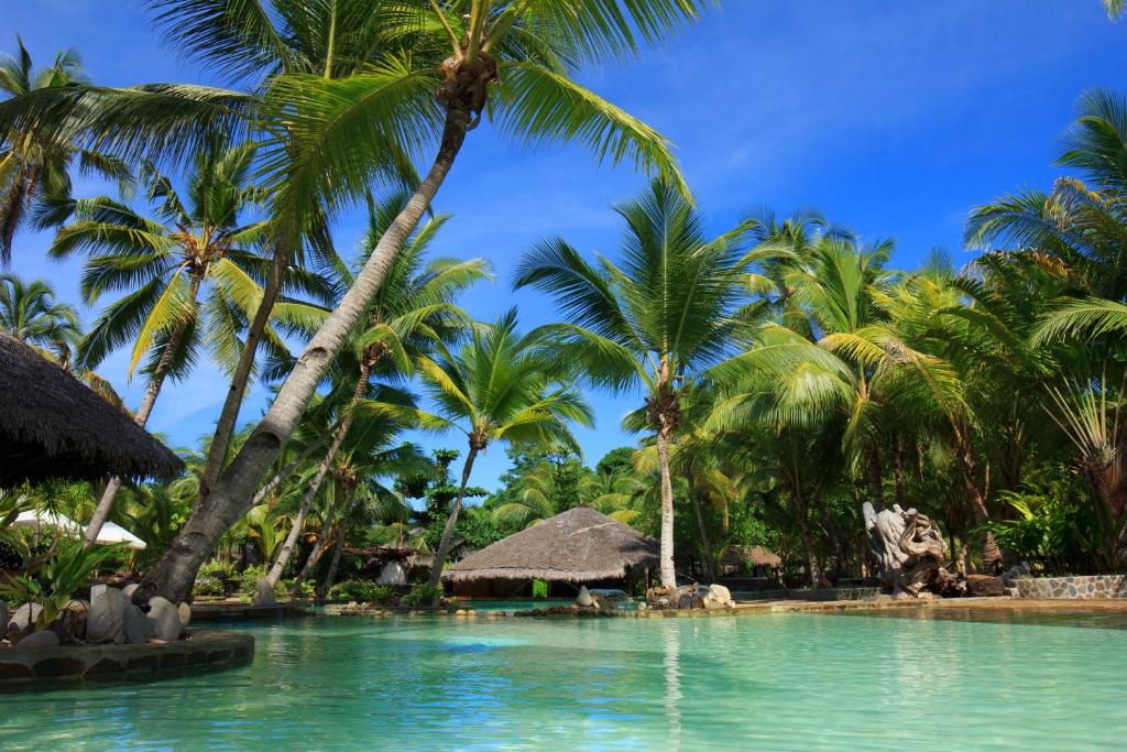 una piscina in un resort con palme di Ravintsara Wellness Hotel a Ambaro