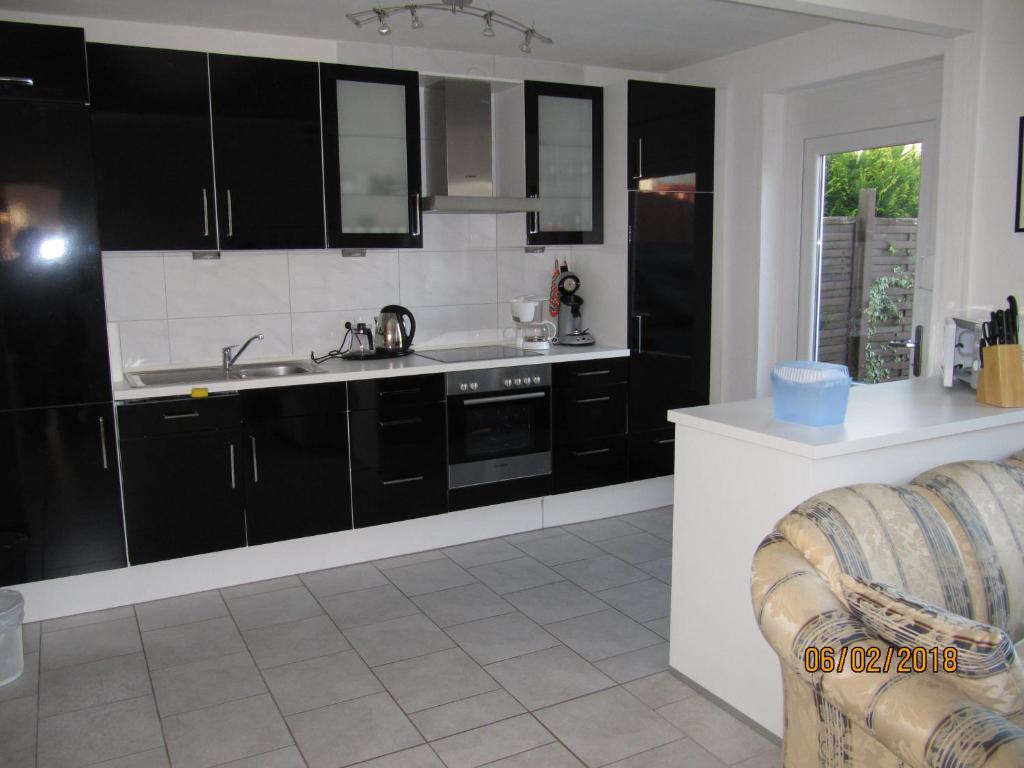 una cocina con armarios negros y fregadero en Ferienhaus Fahrrinne 12, en Dornum