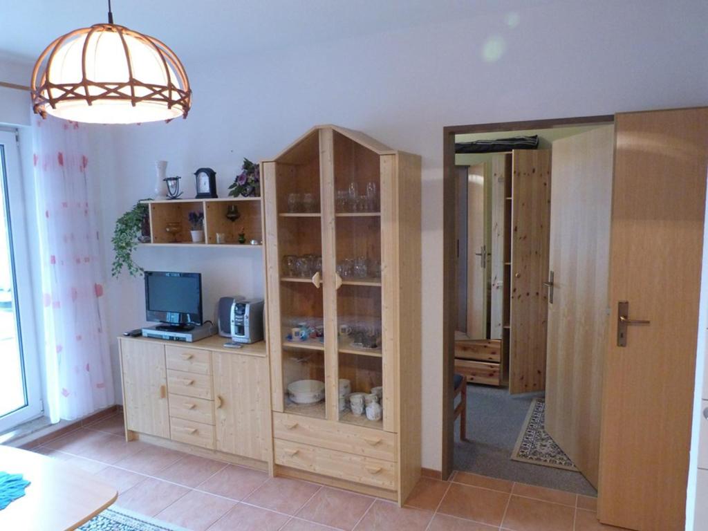 Habitación con armario de madera, TV y espejo. en Fehaus Spiekeroog Wohnung 6, en Dornumersiel