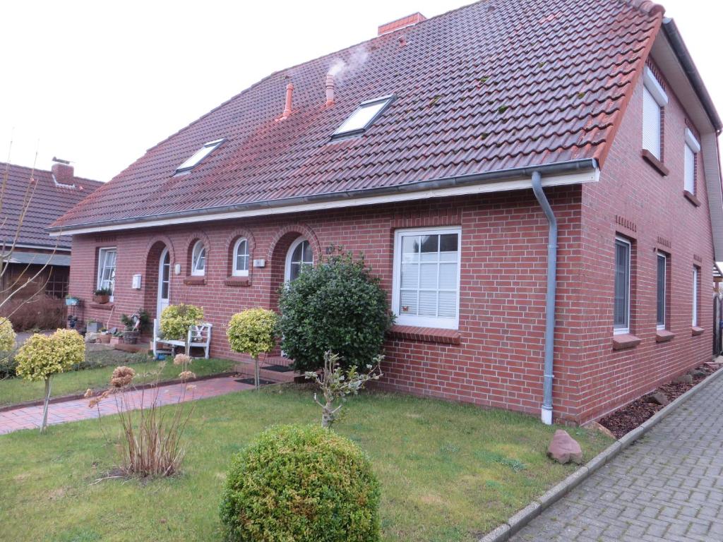 una casa de ladrillo con techo rojo y patio en Ferienhaus Meerzeit, en Nessmersiel