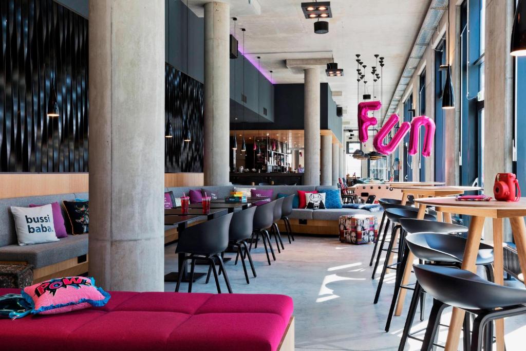 a restaurant with tables and chairs and a red couch at MOXY Vienna Airport in Schwechat