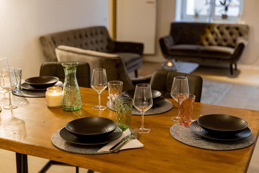 uma mesa de madeira com pratos e copos de vinho em Servus Apartments Old Town Premium em Passau
