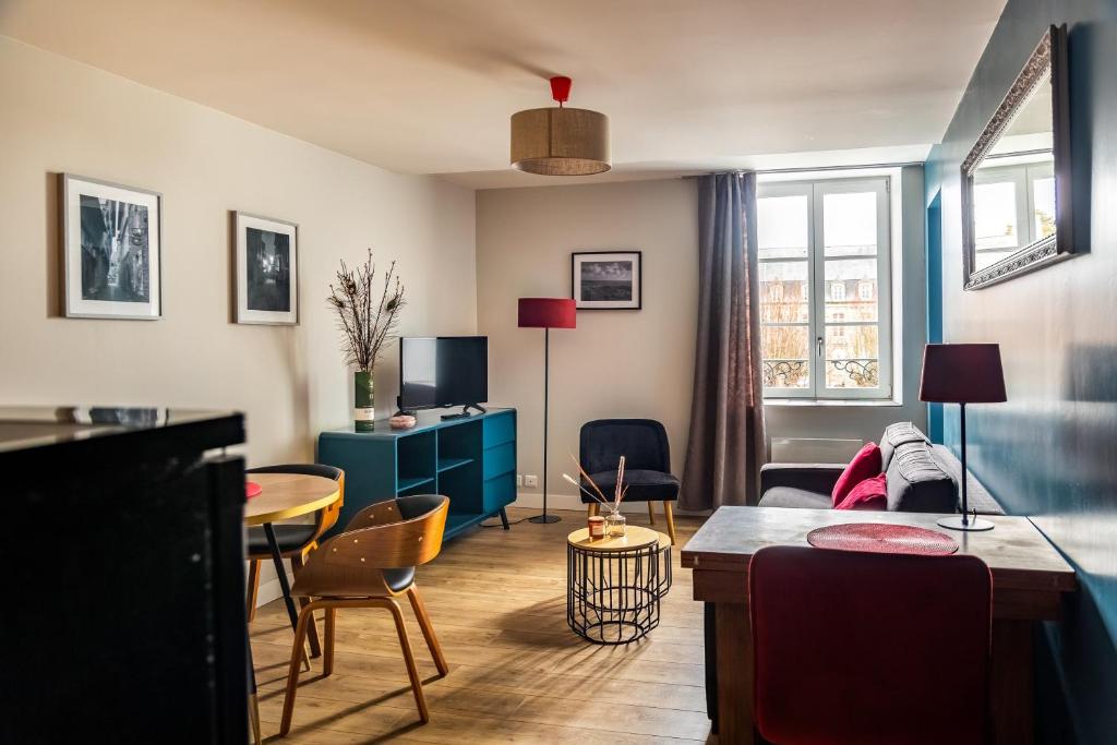 een woonkamer met een bank en een tafel bij Escapade Place 11 - Appartement A2 Dinan centre in Dinan