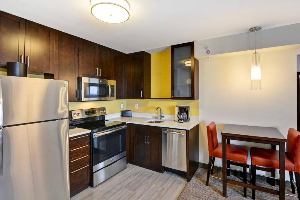 cocina con armarios de madera y nevera de acero inoxidable en Residence Inn by Marriott Milwaukee North/Glendale, en Glendale