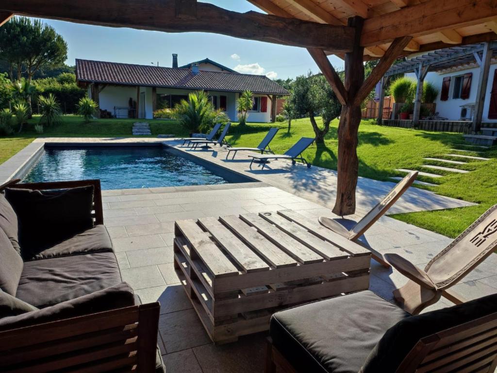 a backyard with a pool with chairs and a pergola at Cosy T2, au calme entre mer et montagnes in Saint-Pée-sur-Nivelle