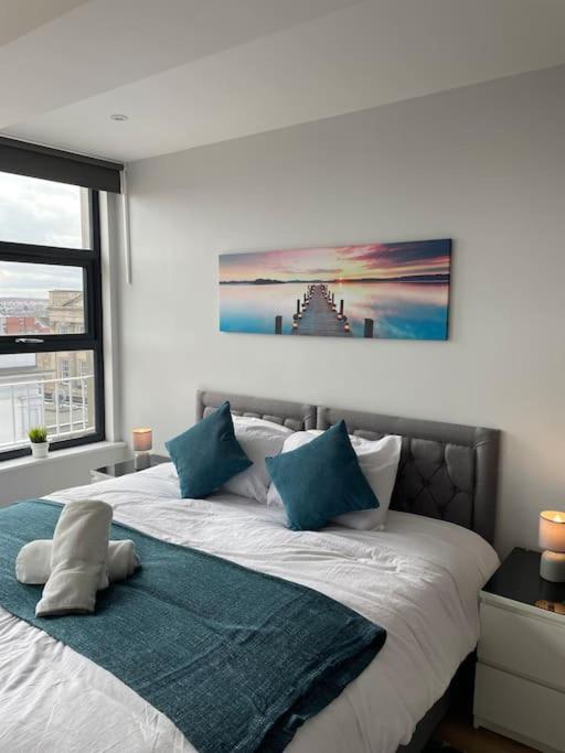 una camera da letto con un grande letto bianco con cuscini blu di King Bed Studio Apartment in Central Northampton a Northampton