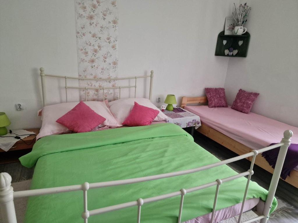 1 dormitorio con cama verde y almohadas rosas en Duna-Lak Vendégház en Apostag