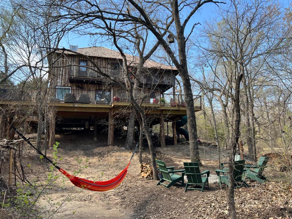 una hamaca frente a una casa en el bosque en "Magical Treehouse" w spiral slide off the deck 350 acres on the Brazos River! Tubing! Petting Zoo! en Weatherford