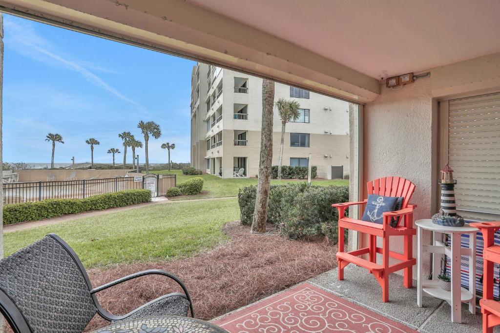 a patio with two chairs and a table and a building at B110 Amelia Surf and Racquet in Fernandina Beach