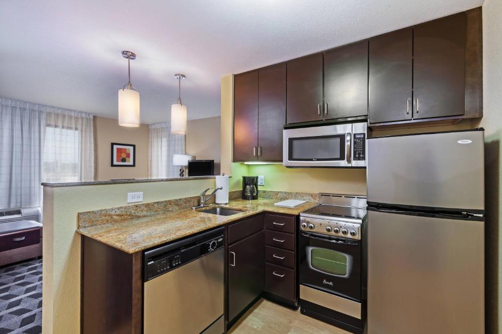 a kitchen with stainless steel appliances and wooden cabinets at TownePlace Suites by Marriott Tulsa Broken Arrow in Broken Arrow