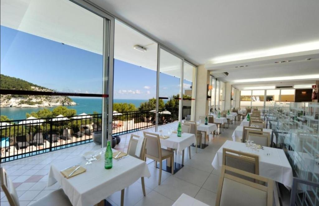 restauracja z białymi stołami i krzesłami oraz balkonem w obiekcie Villetta Relax Pugnochiuso w mieście Vieste