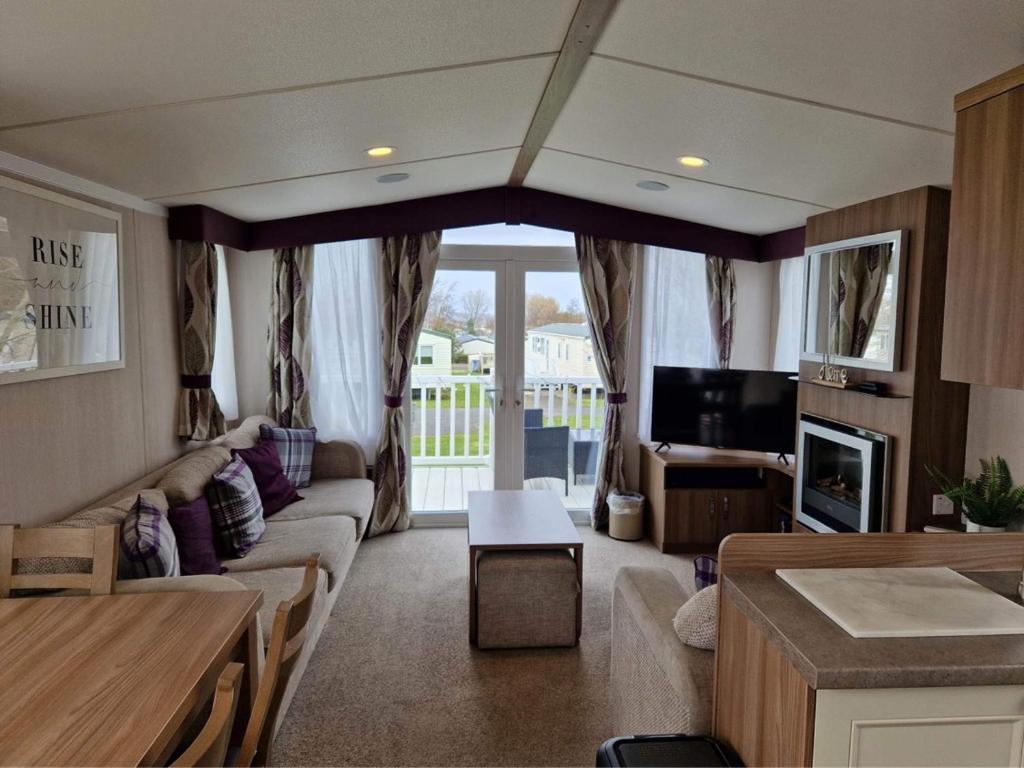 a living room with a couch and a tv at Craig Tara Glen Haven Caravan Dunure Village in Ayr