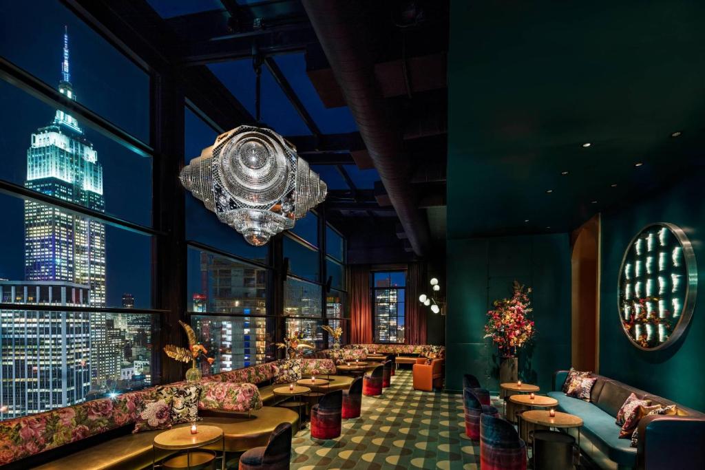 un restaurante con sofás, mesas y una lámpara de araña en Moxy NYC Chelsea, en Nueva York