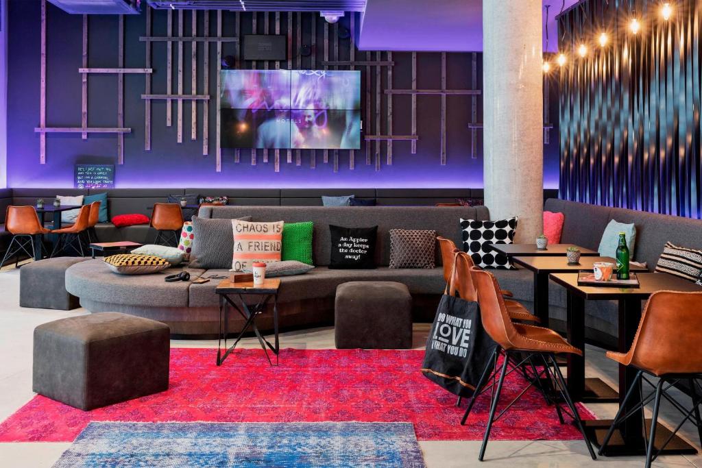 a lobby with a couch and tables and a tv at MOXY Frankfurt East in Frankfurt