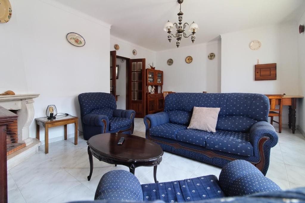 una sala de estar con sofás azules y una mesa. en Casa da Avó, en Vila Nova de Milfontes