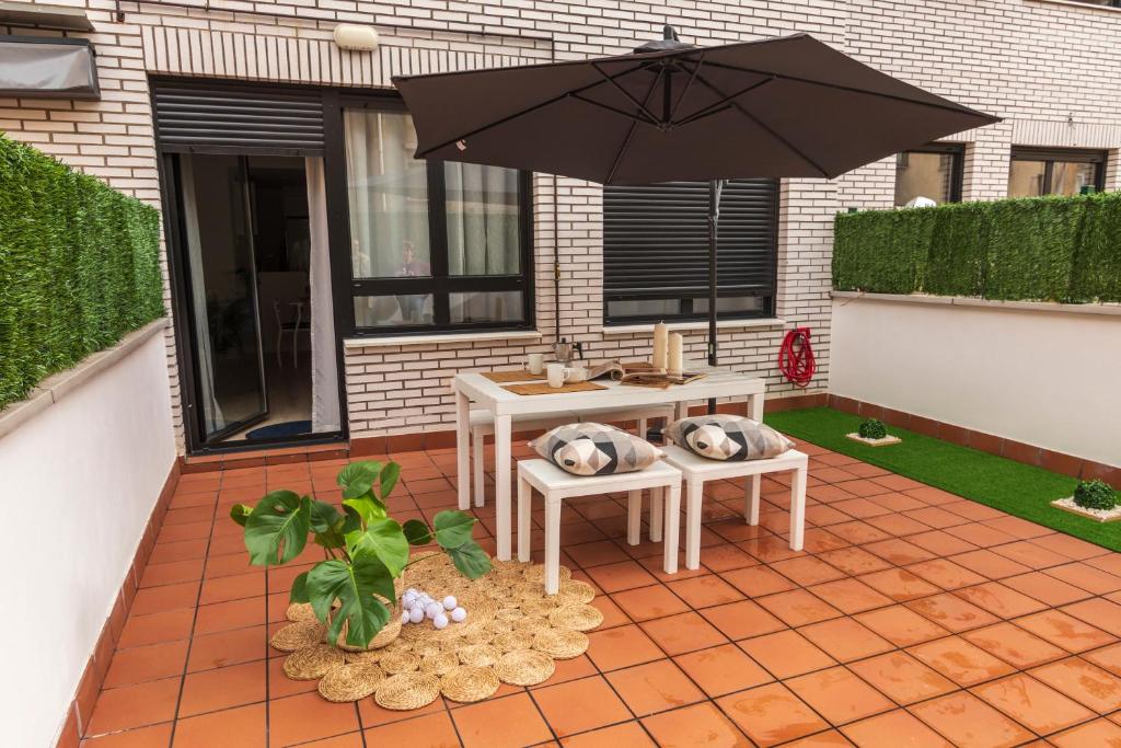 un patio con mesa y sombrilla en LA TERRAZA DE LA VEGA - Ubicación inmejorable , wifi , terraza y parking gratuito en Oviedo