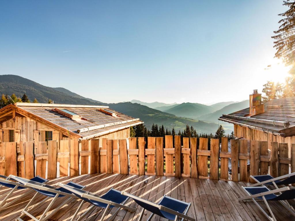 a deck with chairs and a fence and mountains at Holiday Home Schnee Eule-6 by Interhome in Pfarrwerfen