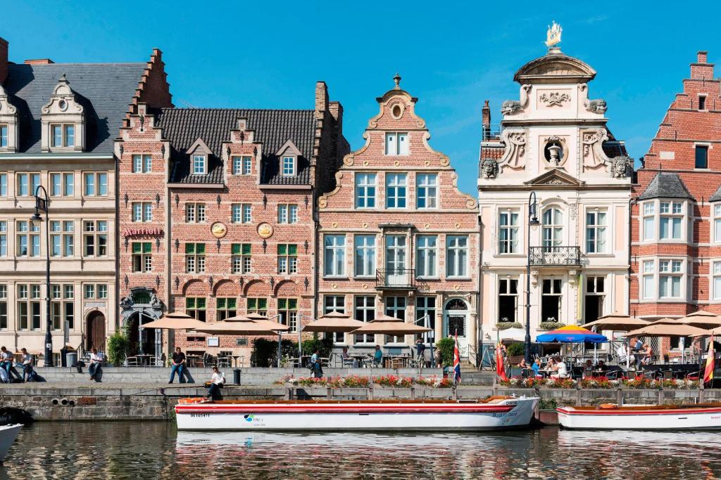 een groep gebouwen naast een rivier met boten bij Ghent Marriott Hotel in Gent
