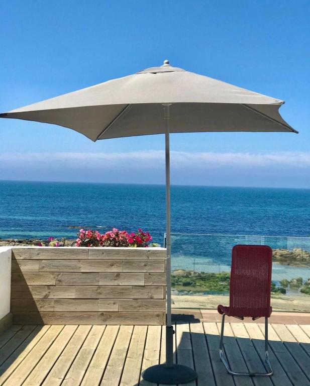 a chair and an umbrella on a deck with the ocean at Casa de Chanquete in Viana do Castelo