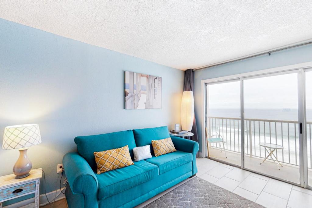 a living room with a blue couch and a balcony at Islander W 703 in Fort Walton Beach