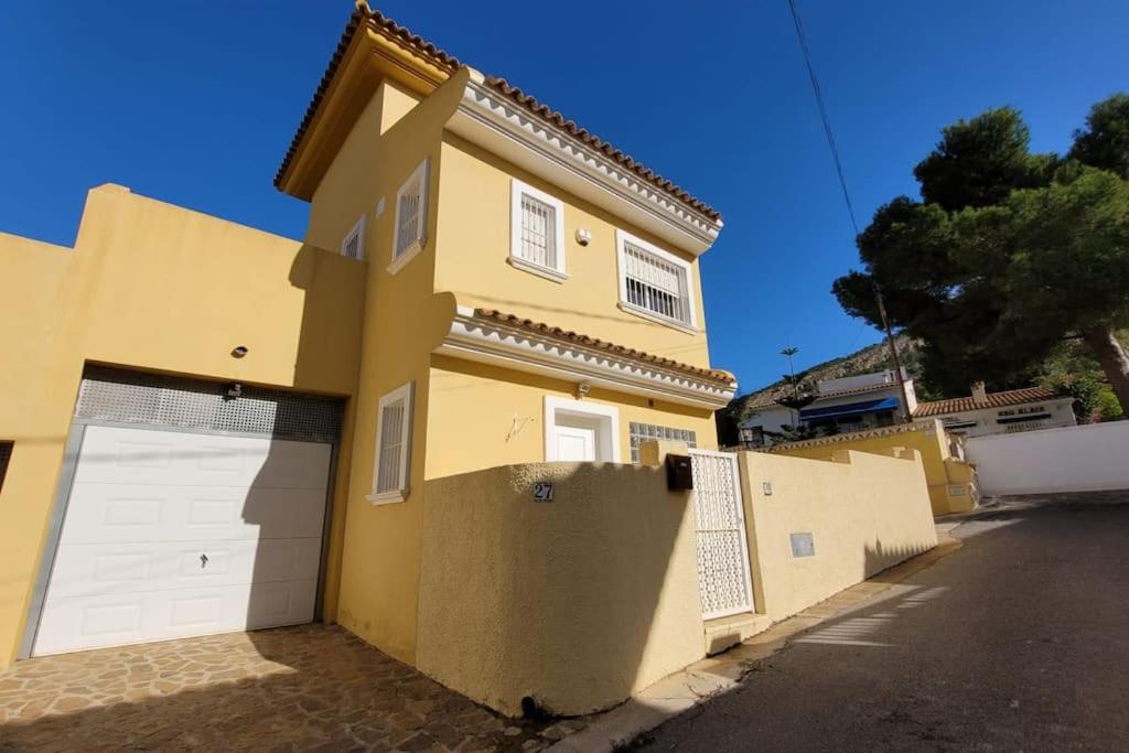 una casa amarilla con dos puertas de garaje en una calle en SHA Villa with private pool , Albir, en Albir