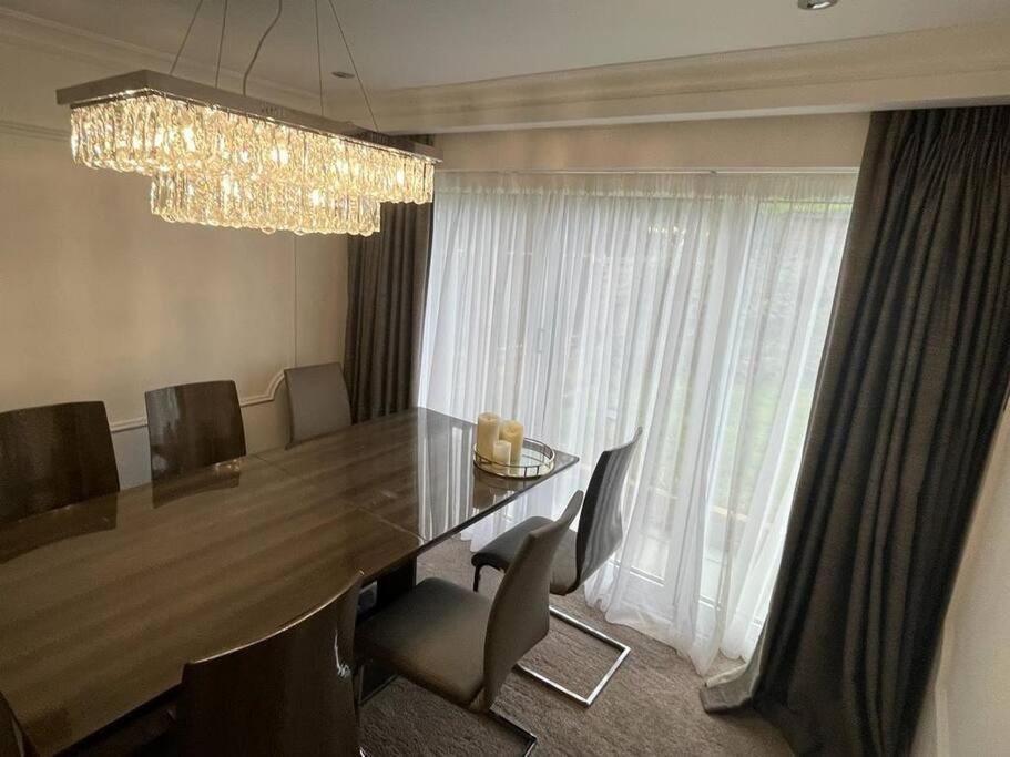 a dining room with a table and chairs and a chandelier at Lovely 3 bedroom house in Borehamwood . in Borehamwood