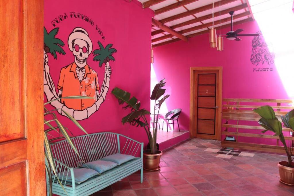 a room with a pink wall with a painting on it at Planet B Hostel - Adults Only in Manuel Antonio