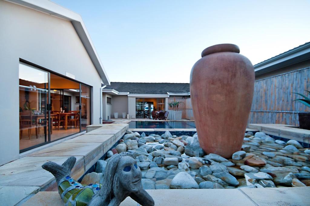 a home with a swimming pool and a large vase at Africa Beach B&B in Port Elizabeth