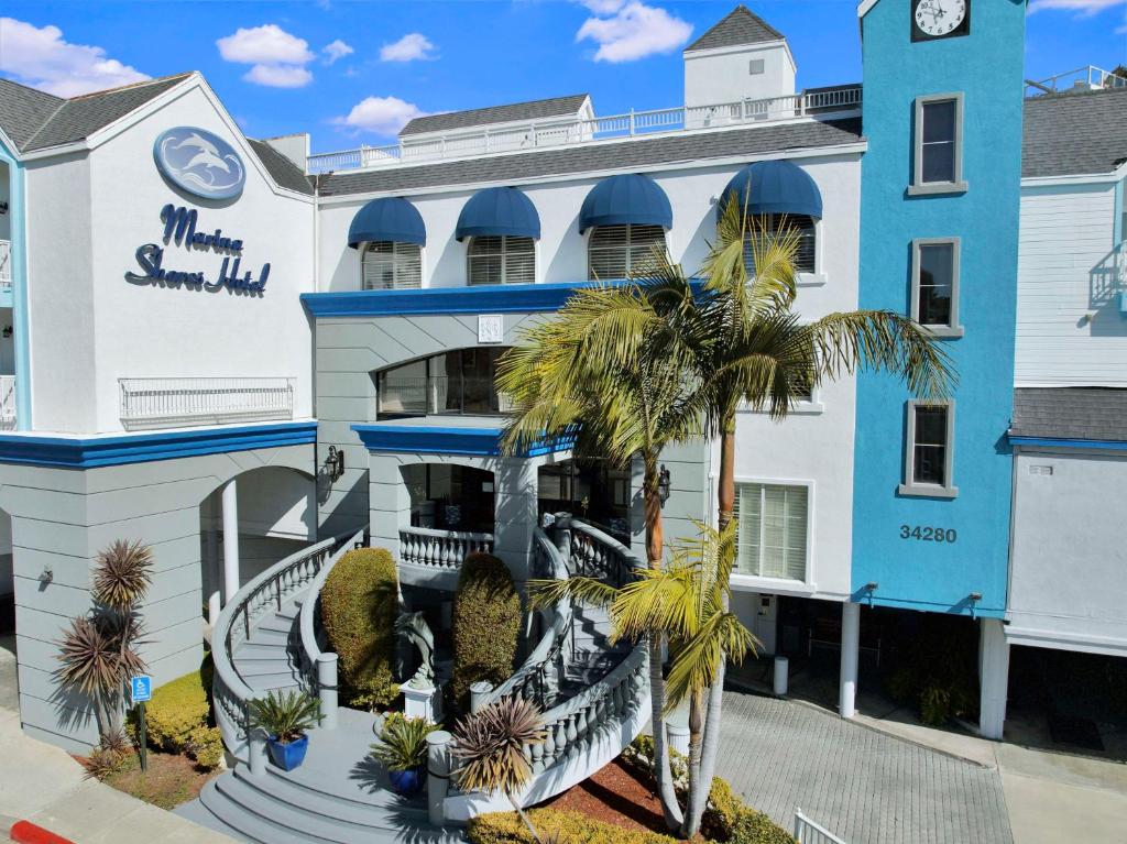 un edificio blu e bianco con palme di fronte di Best Western Plus Marina Shores Hotel a Dana Point