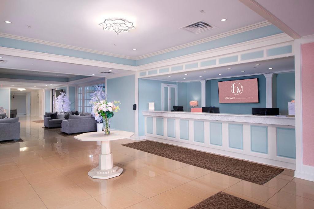 un vestíbulo con una zona de espera con un jarrón de flores sobre una mesa en Bella Vista Hotel & Suites, en Lynchburg