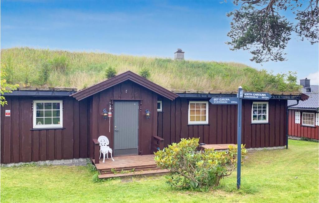 una casa con techo de hierba con un perro en el porche en Awesome Home In Ingeberg With Kitchen en Syljuset