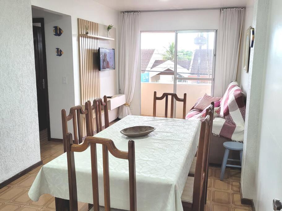 a dining room with a table and chairs and a window at Apartamento Brejatuba Beira Mar in Guaratuba