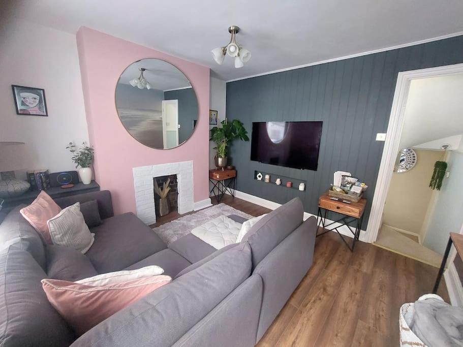uma sala de estar com um sofá cinzento e uma parede rosa em Clifftop Mews - Westcliff - Ramsgate - Pet friendly! em Kent