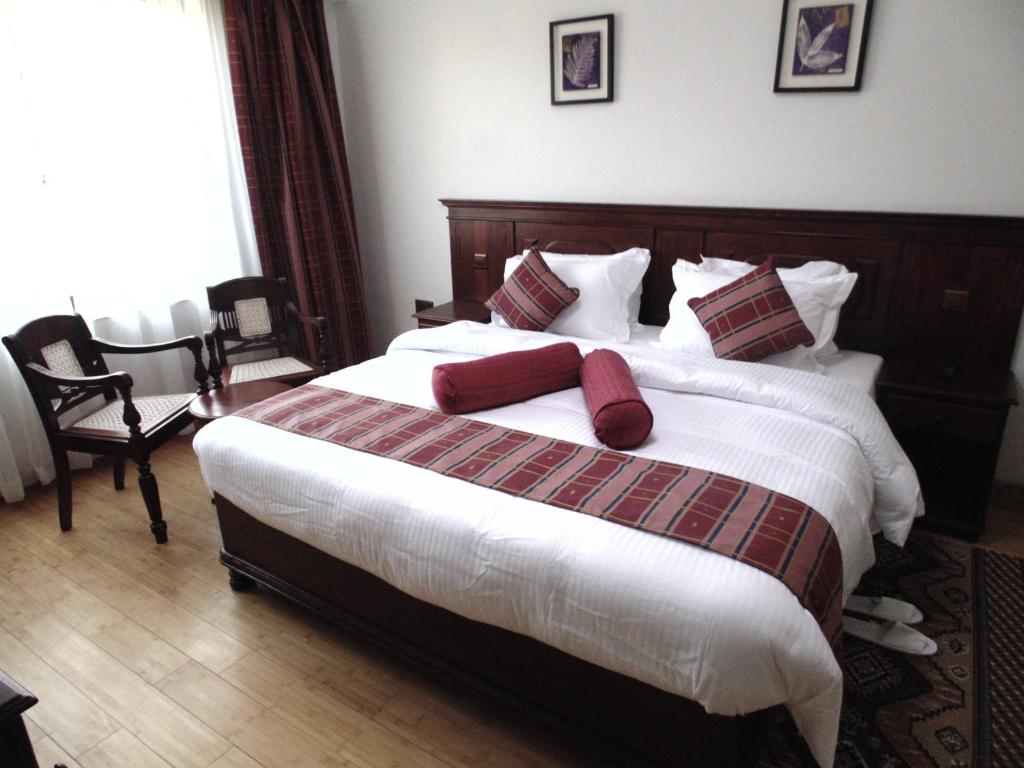 a bedroom with a large bed with red pillows at Eagle Palace Hotel in Nakuru