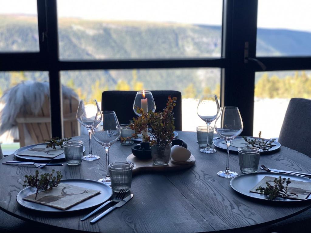 a wooden table with wine glasses and plates on it at Gaustablikk Sportshytte midt i naturen in Rjukan